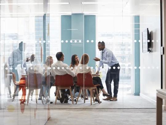 équipe dans une salle de réunion en verre discutant d’un projet