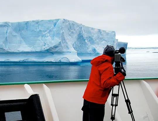 Personne prenant une photo d’un iceberg depuis un bateau