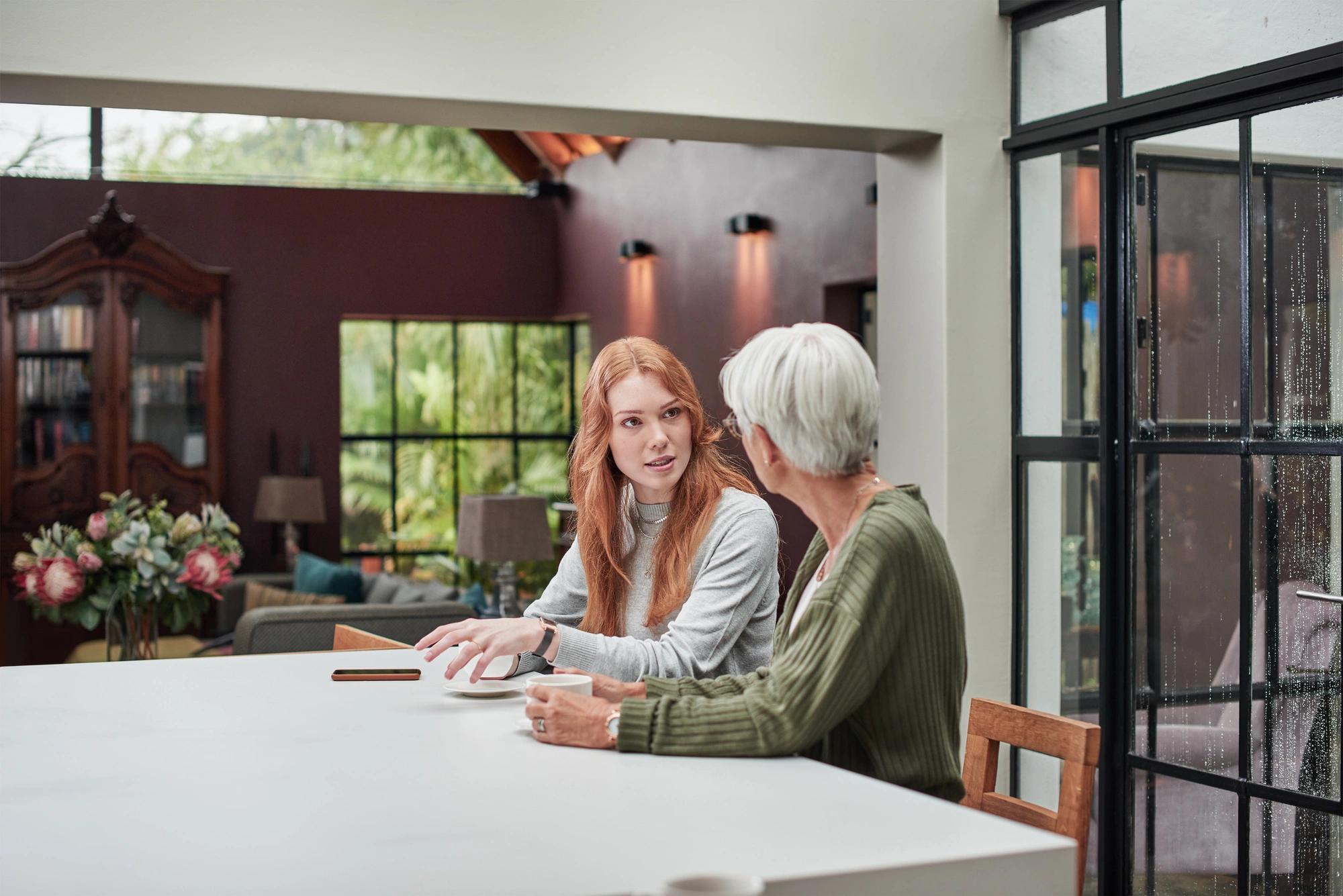 A younger woman and an older woman talking together at a table.