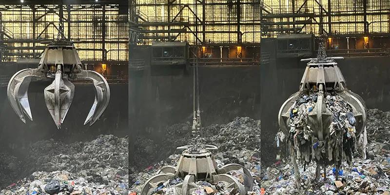 Un grappin est accroché à une grue à l’intérieur d’une installation industrielle, placée au-dessus d’une fosse remplie de déchets.